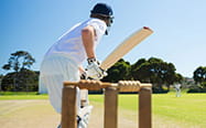 Cricketer in front of the stumps swinging for the ball