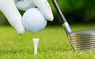 A golf player placing the ball on the tee
