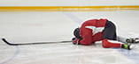 A player lays facedown on the rink after taking a puck in the face.