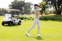 A girl playing golf on the fairway