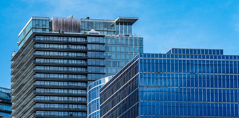 Beberapa gedung pencakar langit kantor berlatar langit biru tak berawan