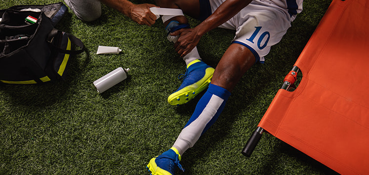 A footballer lying on the ground with a leg injury.