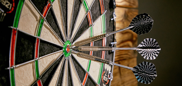 A picture of a dart board with three darts in the bullseye