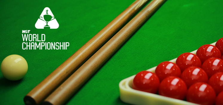 A snooker table scene showcasing two wooden cue sticks, a white cue ball, and a triangle rack filled with red balls on the green felt surface. The WST World Championship logo is prominently displayed in white text on the left side of the image, emphasising the event's branding.