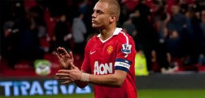 Former Manchester United defender Wes Brown clapping, wearing the red AON sponsored kit.